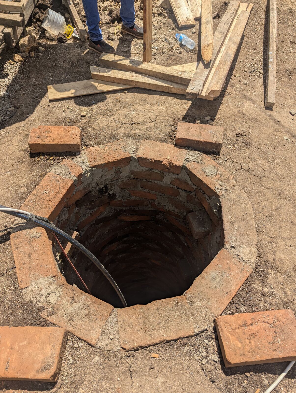 Brick-lined well opening with scaffolding for the masonry housing